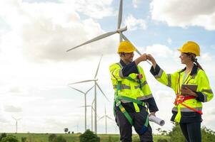 Smart engineers with protective helmet giving fist bump at electrical turbines field photo
