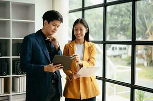 Two  Asian business  man and woman workers talking on the smartphone and using laptop Professionals in Teamwork  Finance, Marketing, and Success photo