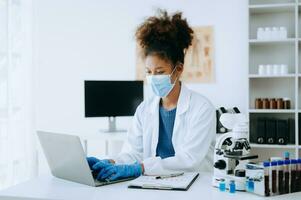 Modern medical research laboratory. African female scientist working with micro pipettes analyzing biochemical samples, advanced science chemical laboratory for medicine. photo