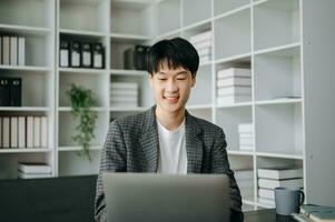 joven negocio hombre trabajando a moderno oficina con computadora portátil, tableta y tomando notas en el papel. foto