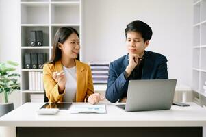 Two Asian business woman and man  discuss investment project working and planning strategy with tablet laptop computer in office. photo