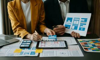 Close up view of UI developer team brainstorming on their project with laptop, smartphone and digital tablet. Creative digital development agency. photo