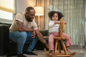 Happy African American man playing with his daughter in living room at home photo