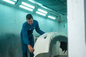 Caucasian man is cleaning car parts before spraying color in repair mechanic painting shop photo