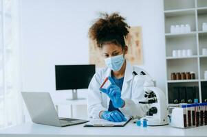 Modern medical research laboratory. African female scientist working with micro pipettes analyzing biochemical samples, advanced science chemical laboratory for medicine. photo