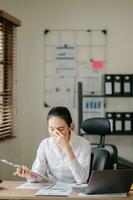 Asian business woman is stressed, bored, and overthinking from working on a tablet at the  office. photo