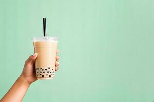 A hand holding takeaway plastic cup of delicious iced bubble milk tea and black pearls with copy space. ai generated photo