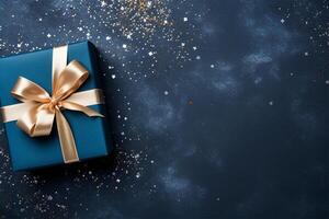 Elegant blue present box with golden bow on a dark blue background, copy space. Gift box, top view. photo