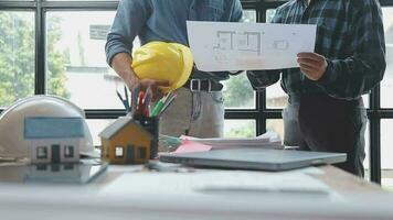 beeld van team ingenieur cheques bouw blauwdrukken Aan nieuw project met bouwkunde gereedschap Bij bureau in kantoor. video