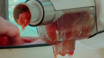 haciendo hecho en casa Fresco tomate jugo con eléctrico máquina. separación de ladrar y semillas desde Tomates jugo. video