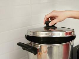 chef hand is opening metal silver pot lid in the white clean kitchen, home kitchen cooking concept photo