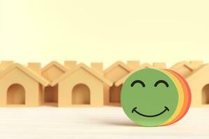 Very satisfied emoji with a sample house model background. Concept of evaluating services provided by clients, for the best housing options and operational efficiency. or credit satisfaction. photo