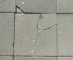 Broken concrete footpaths brick surface background. close up cracked cement block texture photo