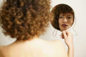 Charming woman with makeup looking reflection in mirror photo