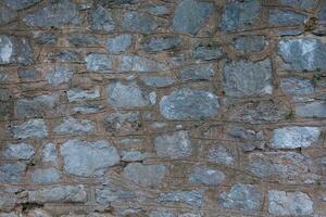 Stone walls are made of huge large bricks with concrete and cement. Sturdy building structure. Textured background with close-up details photo