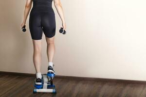 Home fitness. A woman training on a stepper at home. back view photo