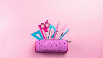 School supplies sticking out of the pencil case pencils, rulers, paper clips, scissors, corrector. banner copy space, pink flat lay photo