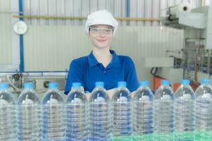 Portrait of a smiling Caucasian technologist expert standing by an automated machine for PET water production in a bottling factory. photo