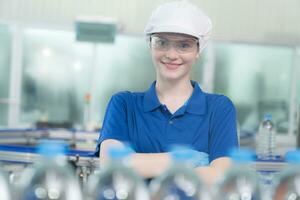 Portrait of smiling Caucasian technologist expert standing by automated machine for PET water production in a bottling factory. photo