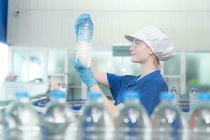 Portrait of a smiling Caucasian technologist expert standing by an automated machine for PET water production in a bottling factory. photo