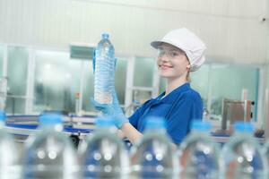 Portrait of a smiling Caucasian technologist expert standing by an automated machine for PET water production in a bottling factory. photo