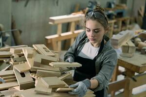 Hardworking carpenter woman using tools smiling confidently young female joiner in apron standing near workbench working in the craft workshop photo