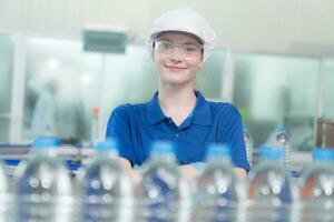 Portrait of a smiling Caucasian technologist expert standing by an automated machine for PET water production in a bottling factory. photo