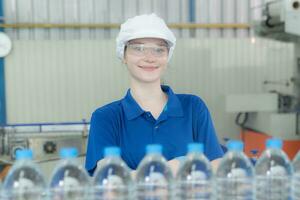 retrato de un sonriente caucásico tecnólogo experto en pie por un automatizado máquina para mascota agua producción en un embotellado fábrica. foto