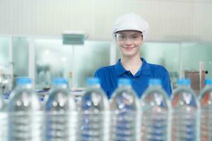 Portrait of a smiling Caucasian technologist expert standing by an automated machine for PET water production in a bottling factory. photo