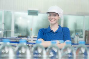 Portrait of smiling Caucasian technologist expert standing by automated machine for PET water production in a bottling factory. photo