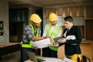 Engineers are discussing data working and laptop or tablet with architectural project at new construction site on big project. interior photo