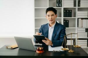 Attractive young lawyer in office Business man and lawyers discussing contract papers laptop and tablet with brass scale on  desk in modern office. Law, legal services, advice, photo