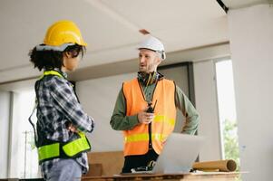 Architect caucasian man and woman working with colleagues mixed race in the construction site. Architecture engineering on big project. Building in construction process interior. photo