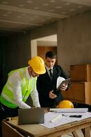 Engineers are discussing data working and laptop or tablet with architectural project at new construction site on big project. interior photo