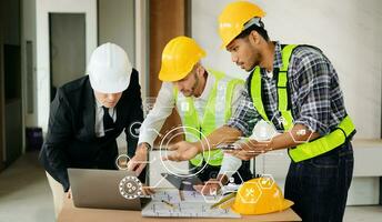 tres colegas discutiendo el trabajo de datos y la tableta, la computadora portátil con el proyecto arquitectónico en el sitio de construcción en el escritorio de la oficina foto