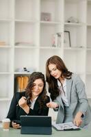Businesswoman leading team meeting and using tablet and laptop computer with financial in coworking office photo