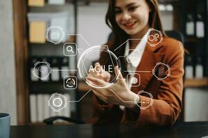 ágil desarrollo metodología concepto. negocio mano utilizando ordenador portátil computadora y tableta con virtual pantalla ágil icono en moderno oficina digital tecnología concepto. foto