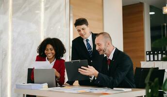 Happy businesspeople while collaborating on a new project in an office. Group of diverse businesspeople using a laptop and tablet in office. photo