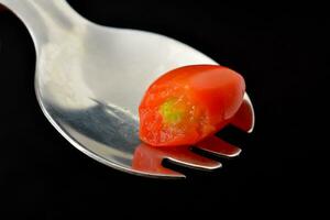 grape tomatoes. Black background with bite marks photo