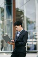 Confident Asian man with a smile standing holding notepad and tablet at the modern office. photo