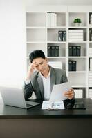 joven hombre de negocios frustrado que trabaja en una computadora portátil sentado en su lugar de trabajo en la oficina foto
