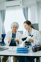 Two scientist or medical technician working, having a medical discuss meeting with an Asian senior female scientist supervisor in the laboratory with online reading, test samples and innovation photo