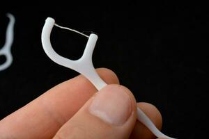 dental floss with pick, white, black background photo