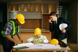 Contractor and architect looking at plan, tablet, laptop and talking about working on big project. Building in construction process photo