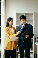 Two Asian business woman and man  discuss investment project working and planning strategy with tablet laptop computer in office. photo