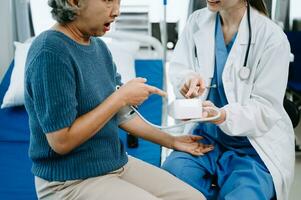 Female senior doctor holding male patient hand on the bed with receiving saline solution in hospital photo