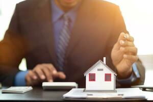 The real estate agent is reviewing the documents and calculating the interest rate to inform the tenant of the monthly installments to be paid before the real estate purchase agreement is finalized. photo