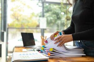 secretary searches through stacked documents on desk in office to find lease within stacked documents just before meeting. concept difficulty in finding hire purchase contract from stacked documents photo