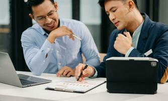 Businessman hand using smartphone, laptop and tablet with social network diagram and two colleagues discussing data on desk as concept photo