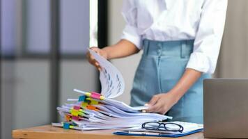 secretary searches through stacked documents on desk in office to find lease within stacked documents just before meeting. concept difficulty in finding hire purchase contract from stacked documents photo